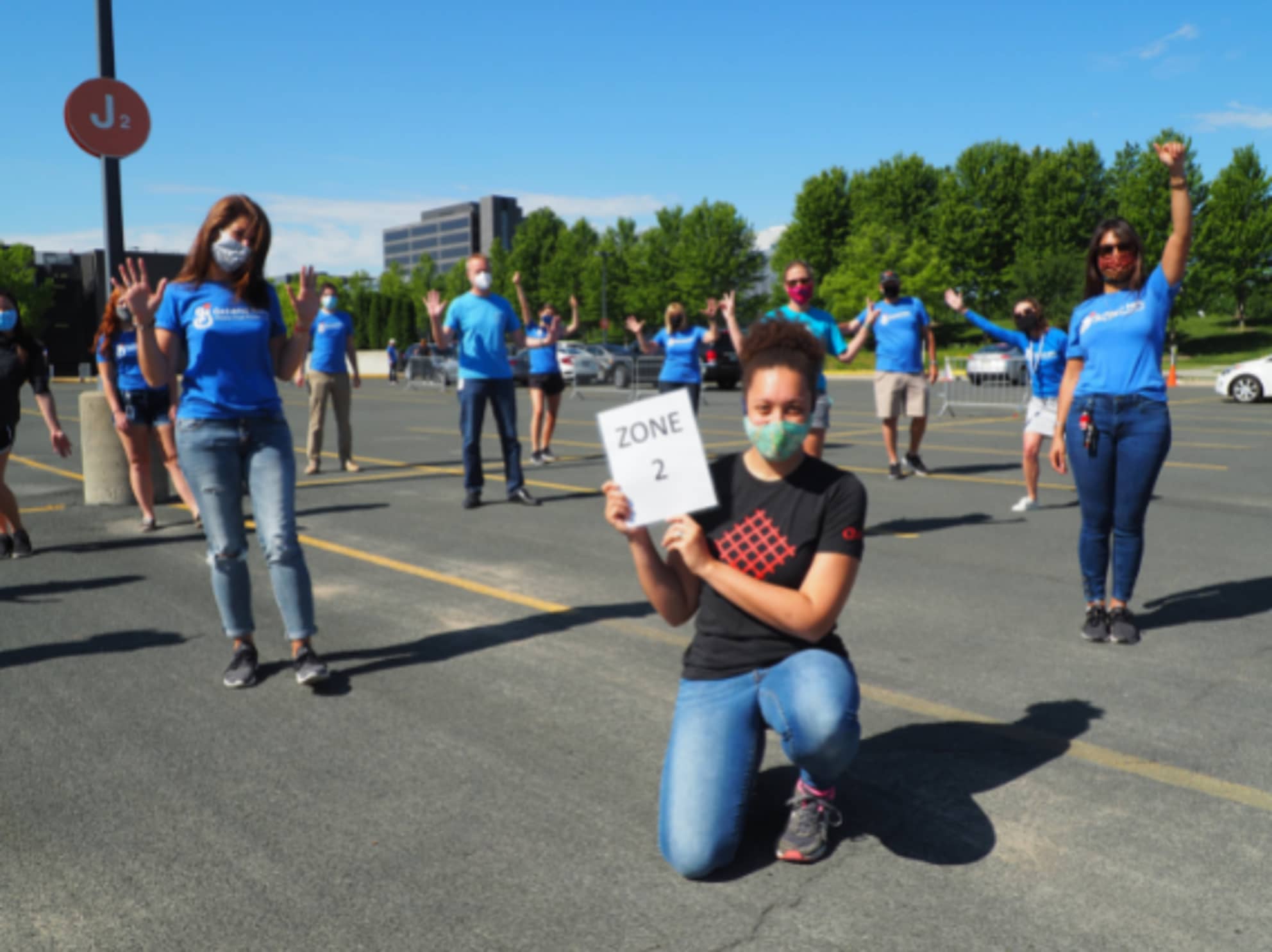 Employees standing distanced waving at camera